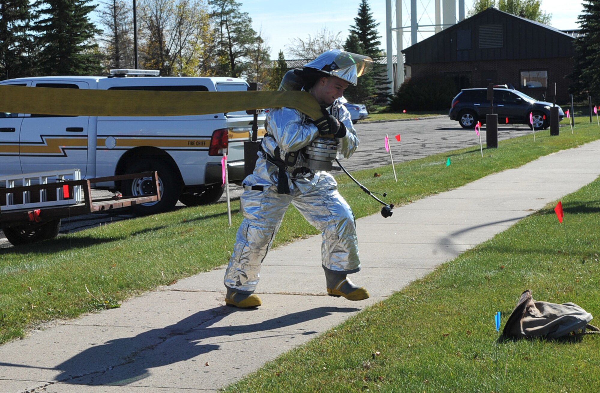 Airman Justin House, 319th Civil Engineer Squadron firefighter apprentice, carries a hose attached to a fire truck toward the nearest fire hydrant as a part of a fire training exercise that took place during Fire Prevention Week at Grand Forks Air Force Base, N.D., Oct. 8, 2014. The Grand Forks AFB Fire Department kicked off the Fire Prevention Week Oct. 3, emphasizing the importance of fire prevention and safety. (U.S. Air Force photo/Airman 1st Class Bonnie Grantham)