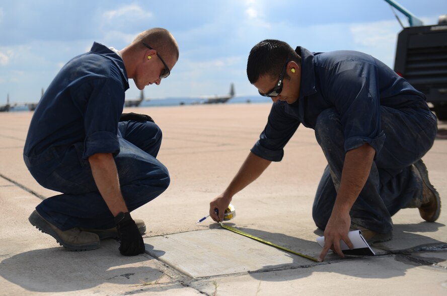 U.S. Air Force Senior Airman Jacob Mullin, left, and Senior Airman Nolan Nunez, both 7th Civil Engineer Squadron pavements and heavy repair journeymen, measure a patch of concrete Sept. 29, 2014, at Dyess Air Force Base, Texas. This measurement is needed to keep track of how much material was used to repair a section of the concrete. (U.S. Air Force photo by Airman 1st Class Kedesha Pennant/Released)
