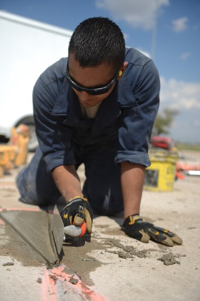U.S. Air Force Senior Airman Nolan Nunez, 7th Civil Engineer Squadron pavements and heavy repair journeyman, uses a trowel to smooth newly-poured concrete Sept. 29, 2014, at Dyess Air Force Base, Texas. Several small sections of concrete pad on the flight line were replaced to prevent damage to aircraft and further erosion.  (U.S. Air Force photo by Airman 1st Class Kedesha Pennant/Released)