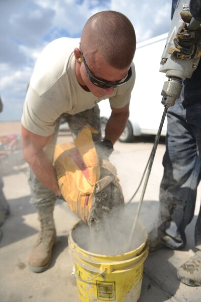 U.S. Air Force Airman 1st Class Benjamin England, 7th Civil Engineer Squadron pavements and heavy repair journeyman, empties concrete mix into a bucket of water Sept. 29, 2014, at Dyess Air Force Base, Texas. This material is used to replace defective pavement removed during a repair process. (U.S. Air Force photo by Airman 1st Class Kedesha Pennant/Released)