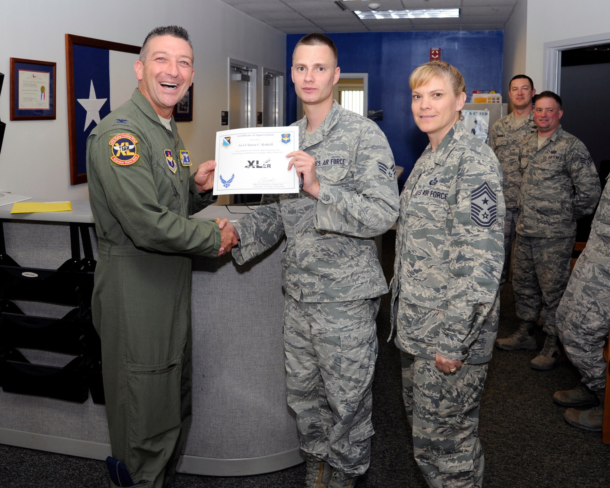 Senior Airman Clinton Rohloff, center, 47th Contracting Flight contract specialist, poses with Col. Brian Hastings, left, 47th Flying Training Wing commander, and Chief Master Sgt. Teresa Clapper, right, 47th FTW command chief, after being presented the XLer of the week award here Oct. 8, 2014. The XLer is a weekly award chosen by wing leadership and is presented to those who consistently make outstanding contributions to their unit and Laughlin. (U.S. Air Force photo by Airman 1st Class Jimmie D. Pike)(Released)