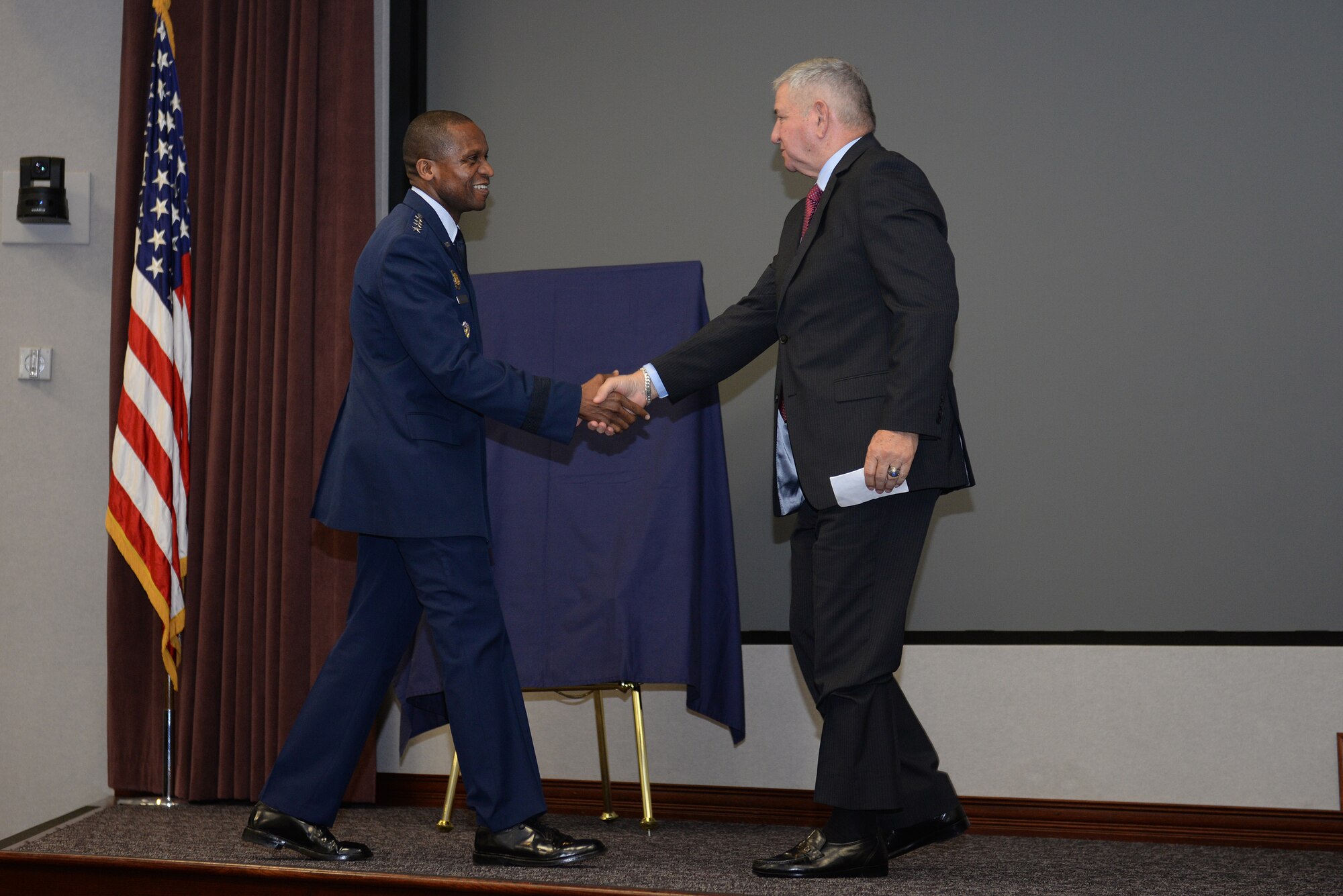 Gen. Darren W. McDew, Air Mobility Command commander, welcomes retired Gen. Ronald R. Fogleman to the stage during Fogleman's induction to the Airlift/Tanker Association Hall of Fame at Scott Air Force Base, Illinois, Oct. 9, 2014. McDew spoke of Fogleman's enduring legacy as the driving force behind the creation of the Air Force Core Values of Integrity First, Service Before Self, and Excellence in All We Do. (U.S. Air Force photo/Airman 1st Class Erica Crossen)