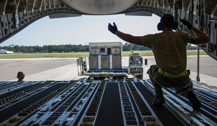 Airman 1st Class Luke Saylors, 437th Aerial Port Squadron air transportation technician, marshals in a 437th Atlas K-Loader towards a C-17 Globemaster III, Oct. 8, 2014, on the flightline at Joint Base Charleston, S.C. In addition to their normal duties of loading and unloading our C-17s, the 437th APS provides support for the nation’s premier rapid deployment forces: XVIII Airborne Corps, 82nd Airborne Division, Joint Special Operations Command and the 43rd Airlift Wing. The squadron is prepared to meet short-notice, worldwide mobility taskings in support of national objectives, and plans and executes support for more than 50 percent of all joint airborne and air transportability training missions flown by Air Mobility Command and Reserve forces in support of Joint Operations. (U.S. Air Force photo/Airman 1st Class Clayton Cupit)