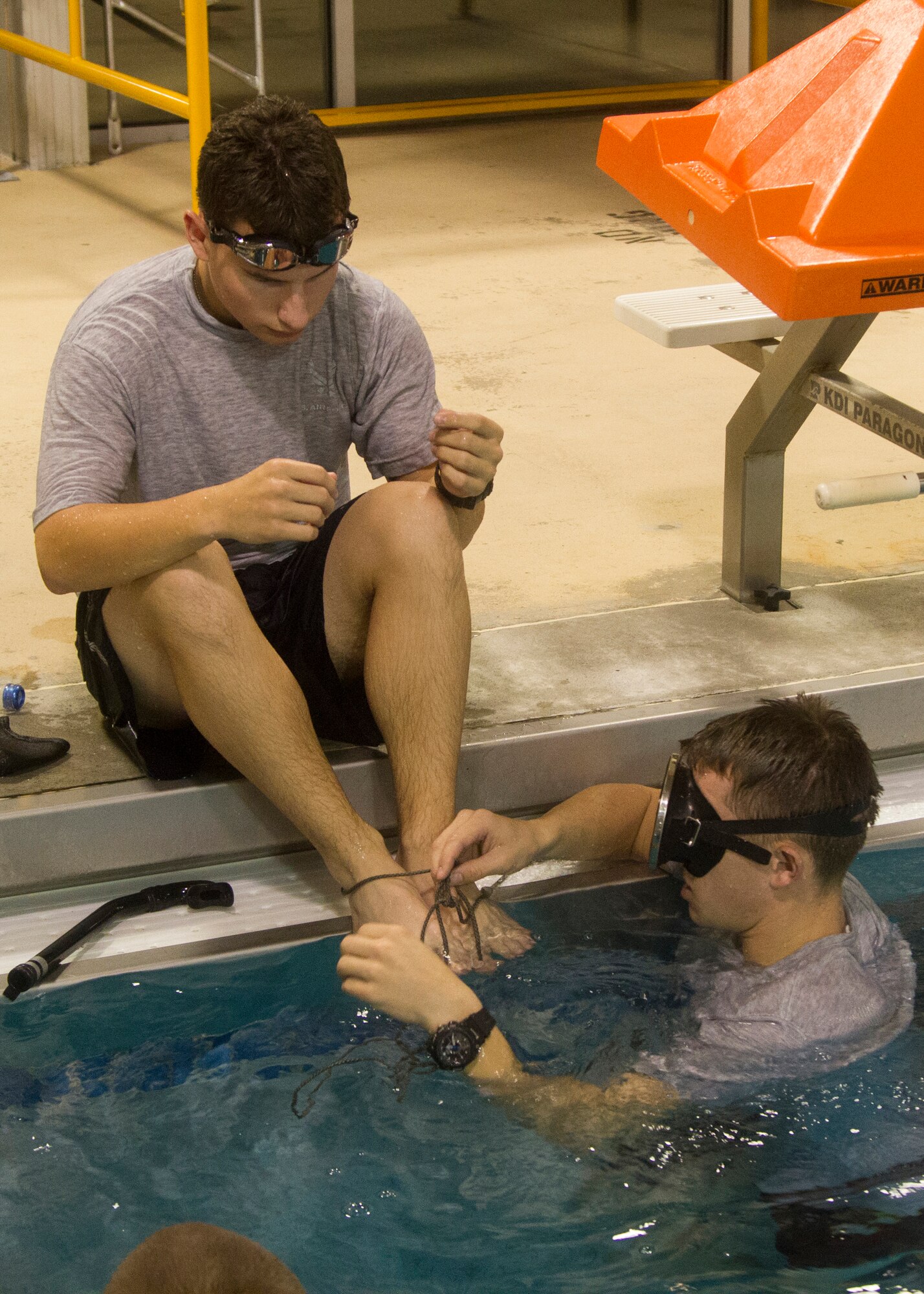 Airman 1st Class Jordan Robinson, a cyber systems operator with the 87th Communication Squadron ties the feet of Airman 1st Class Zachary Baker, also a cyber systems operator with the 87th Communication Squadron, as they prepare to perform partial “Dead Man’s Float” swimming drills at the indoor pool at Joint Base McGuire-Dix-Lakehurst, N.J., Oct. 7, 2014. With their legs tied, Robinson and Baker sink themselves to the bottom of the pool before kicking their way back up for air, then repeating the process for another two minutes. The swimming drills are a part of Robinson’s training regimen as he prepares to attend the selection phase of Air Force Combat Controller School. (U.S. Army photo by Sgt. Ryan Scott/Released)