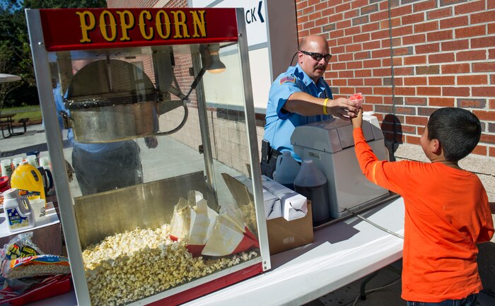 A Joint Base Charleston Fire Department fireman gives out snow-cones to children during a JB Charleston Fire Department fire prevention week event Oct. 7, 2014, at the Air Base Exchange on JB Charleston, S.C. Fire prevention Week was Oct. 5 through 11, and the JB Charleston Fire Department hosted several events around the Air Base and Weapons Station. Fire prevention week was established in 1925 by President Calvin Coolidge when he became aware that close to 15,000 American citizens had been killed in fires the previous year. (U.S. Air Force photo/Airman 1st Class Clayton Cupit)