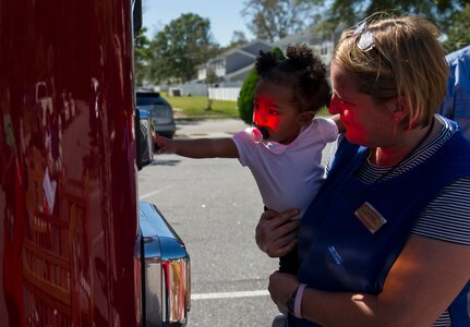 A child from the Brig. Gen. Thomas R. Mikolajcik Child Development Center reaches for a light on a Joint Base Charleston Fire Department fire truck with assistance from a CDC staff member Oct. 6, 2014, at the CDC parking lot on Joint Base Charleston, S.C. Fire prevention Week was Oct. 5 through 11, and the JB Charleston Fire Department hosted several events around the Air Base and Weapons Station. Fire prevention week was established in 1925 by President Calvin Coolidge when he became aware that close to 15,000 American citizens had been killed in fires the previous year. (U.S. Air Force photo/Airman 1st Class Clayton Cupit)