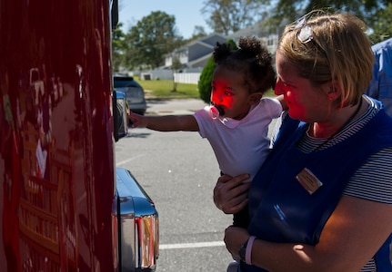 A child from the Brig. Gen. Thomas R. Mikolajcik Child Development Center reaches for a light on a Joint Base Charleston Fire Department fire truck with assistance from a CDC staff member Oct. 6, 2014, at the CDC parking lot on Joint Base Charleston, S.C. Fire prevention Week was Oct. 5 through 11, and the JB Charleston Fire Department hosted several events around the Air Base and Weapons Station. Fire prevention week was established in 1925 by President Calvin Coolidge when he became aware that close to 15,000 American citizens had been killed in fires the previous year. (U.S. Air Force photo/Airman 1st Class Clayton Cupit)