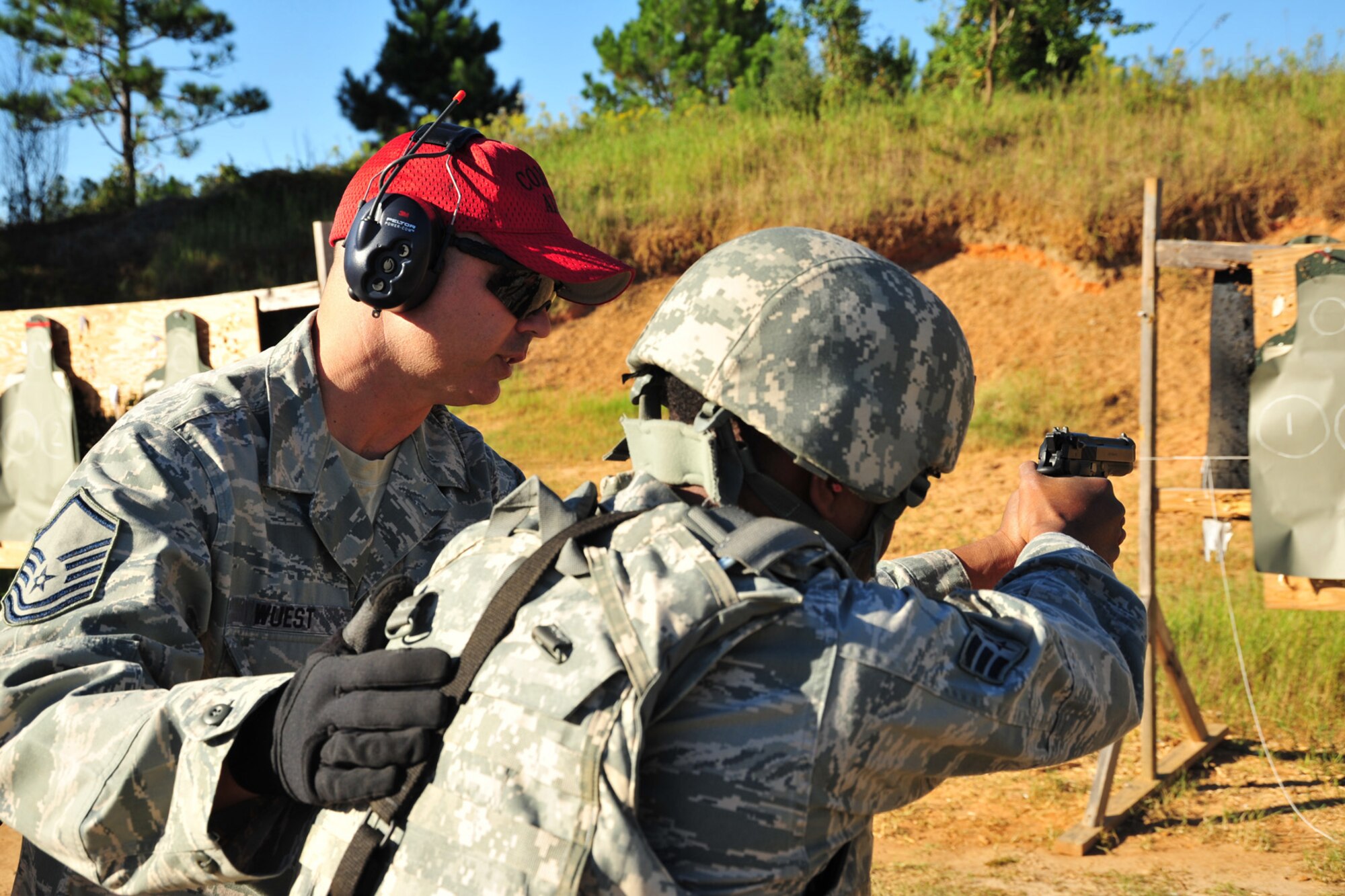 Master Sgt. Joey Wuest, 403rd Security Forces Squadron combat arms instructor, coaches Senior Airman Jerome McDaniel, 403rd Security Forces Squadron fire team member, on swapping rapidly between his M4 carbine and M9 pistol at the Woolmarket U.S. Navy Rifle and Pistol Range, Woolmarket, Mississippi, Oct. 4, 2014. 403rd SFS members, stationed at Keesler Air Force Base, Mississippi, have been fulfilling various training requirements in preparation for their upcoming deployment to Southwest Asia. (U.S. Air Force photo/Tech. Sgt. Ryan Labadens)