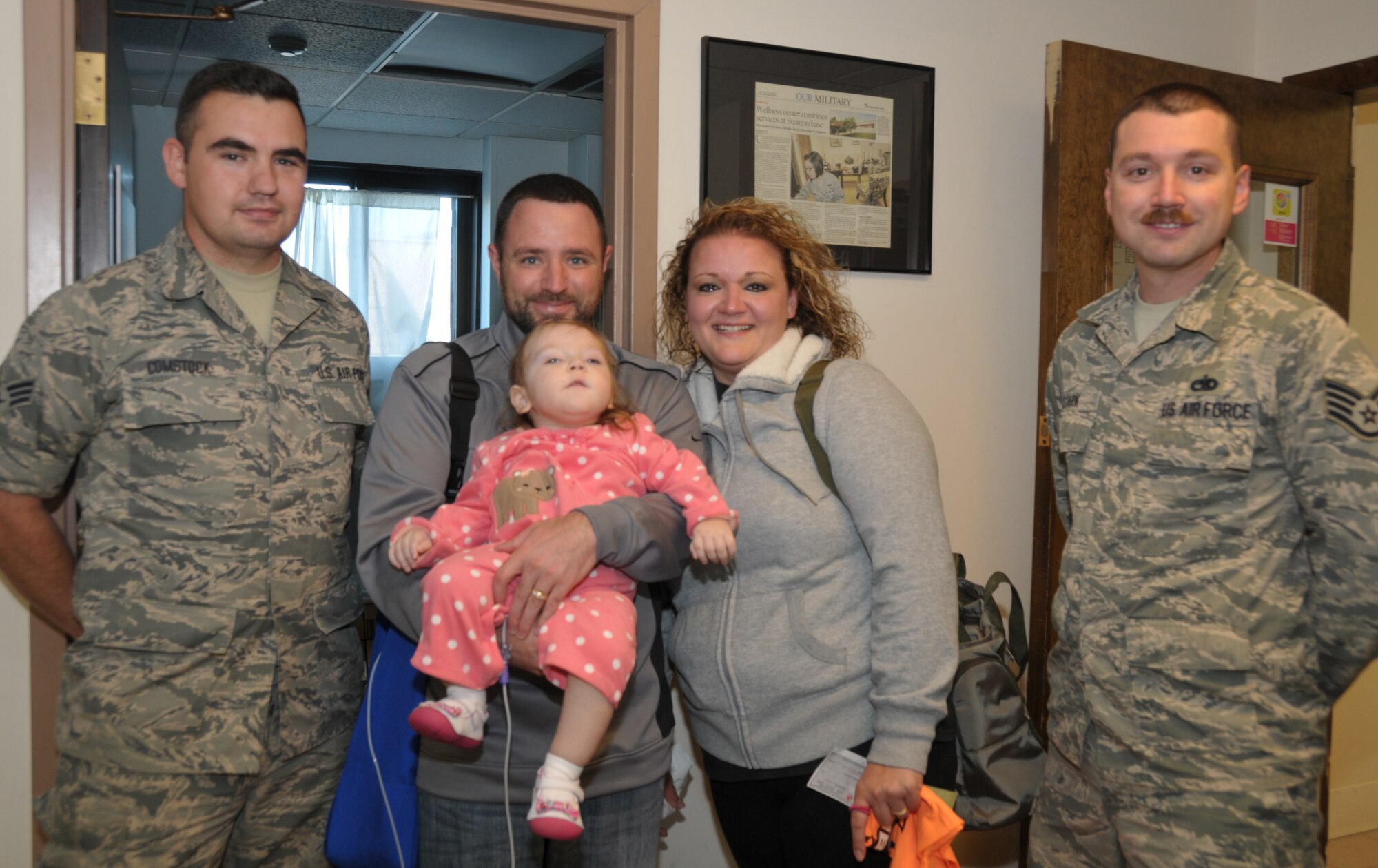 Senior Airman James Comstock (left) and Staff Sgt. Jason Stark (right) presented a check of $500 on behalf of the 109th Airlift Wing's First Six Council to the LeClaire family, Gene, Dena and 22-month-old Sophia. Sophia has cerebral palsy, and the council raised money  during the wing's recent Family Day to help with her medical expenses. (U.S. Air National Guard photo by Tech. Sgt. Catharine Schmidt/Released)