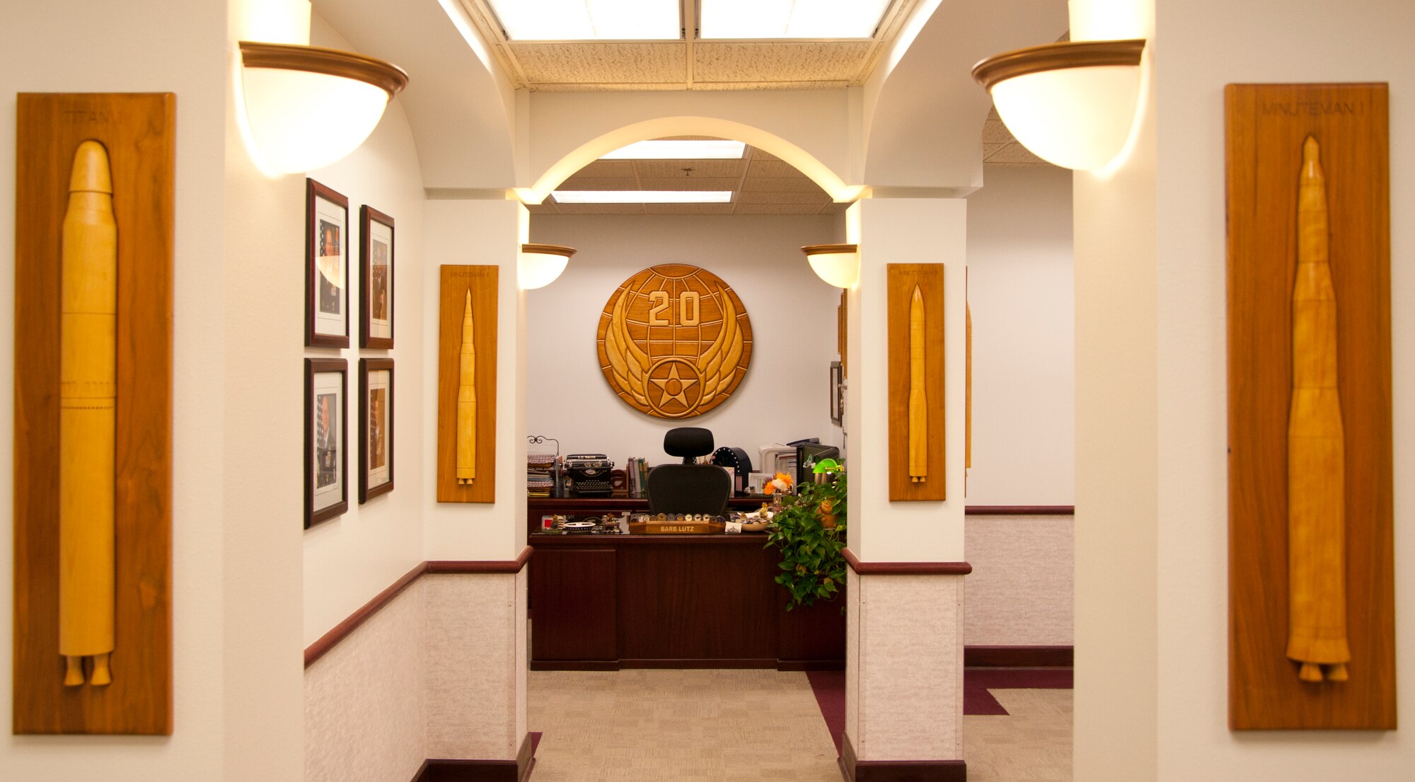 An example of the woodworking skill of the F.E. Warren Arts and Crafts Center wood shop adorns the wall of an F.E. Warren building. Missiles under the care of the 20th Air Force, including the Titan and Minuteman I through III hang on the columns leading down the hallway at the 20th AF headquarters and draw the eye toward the 20th AF patch on the wall in the background.  (U.S. Air Force photo by Senior Airman Jason Wiese)