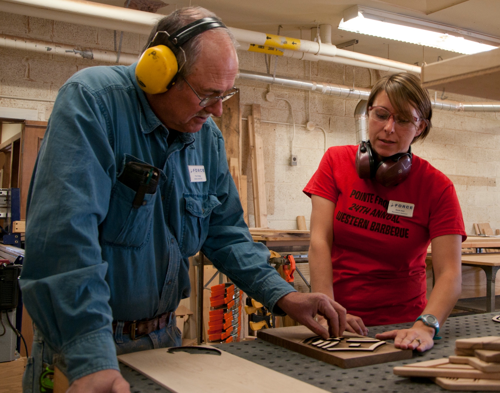 Paul Gregg, 90th Force Support Squadron wood crafter, and Sarah Dyer, 90th FSS recreational assistant, discuss a woodworking project they are working on Oct. 8, 2014. Gregg, Dyer and Dave Holmquist, 90th FSS wood crafter, form the wood shop team at the F.E. Warren Arts and Crafts Center. (U.S. Air Force photo by Senior Airman Jason Wiese)