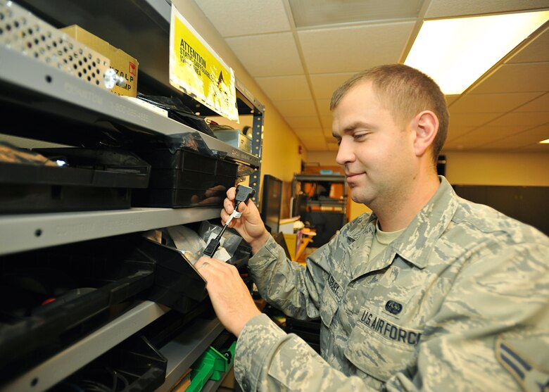 Airman 1st Class Adam Saulsbury, 319th Communications Squadron client system technician, retrieves a dongle cord in order to connect two computer monitors, on Oct. 8, 2014, at the 319th CS CSTR shop on Grand Forks Air Force Base, N.D. Saulsbury was selected as the base's Warrior of the Week for the second week in October 2014. (U.S. Air Force photo/Senior Airman Xavier Navarro)