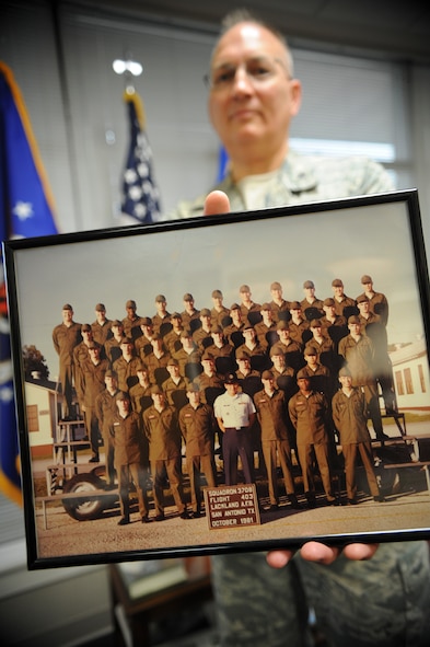 U.S. Air Force Col. Jeffrey Decker, 23d Maintenance Group commander, holds a framed picture of his 1981 basic training flight that hangs in his office Sept. 25 2014, at Moody Air Force Base, Ga. Decker received his commission through the Officer Training School program after eight years as an enlisted avionics specialist. (U.S. Air Force photo by Andrea Jenkins)