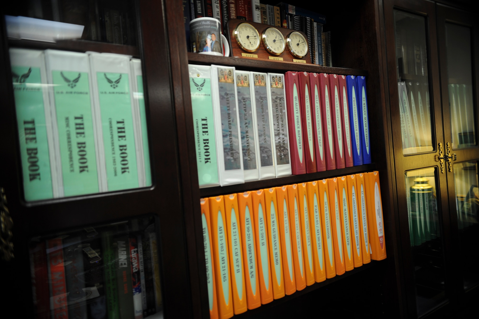 Color-coded maintenance regulations, Air Force Instructions, and history books sit perfectly aligned on the office credenza of U.S. Air Force Col. Jeffrey Decker, 23d Maintenance Group commander, Sept. 25, 2014 at Moody Air Force Base, Ga.  The clock, a gift from his wife Angie, is set for local time, zulu time and the time zones for when his wife is traveling on business. (U.S. Air Force photo by Andrea Jenkins)