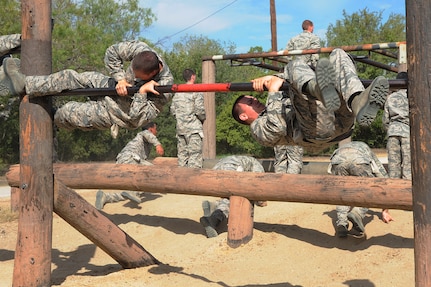 Basic military trainees swing around a bar as part of the basic military training obstacle course at Sept. 24, 2014J Joint Base San Antonio-Lackland. The obstacle course was about a mile to a mile and a half long depending on what 14 obstacles were open. The two water obstacles were closed seasonally. The course was permanently closed the same day and new one was integrated into the Creating Leaders, Airmen, and Warriors, or CLAW program and became fully operational Sept. 29. (U.S. Air Force photo by Senior Airman Krystal Jeffers/Released)