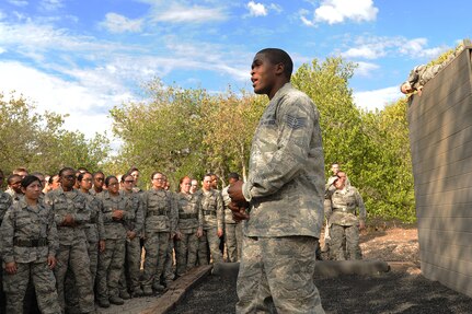 Tech. Sgt. Richard Harding, 319th Training Support Squadron military training instructor and NCO in charge of the basic military training obstacle course, describes how to safely complete one of the obstacles at basic military training obstacle course to trainees while Staff Sgt. Dennis Weis, 323rd Training Squadron military training instructor, demonstrates the actions Sept. 24, 2014 at Joint Base San Antonio-Lackland,. The course, which permanently closed the same day, was replaced with the Leadership Reaction Course at JBSA-Lackland Medina Annex, which became fully operational Sept. 29, 2014. (U.S. Air Force photo by Senior Airman Krystal Jeffers/Released)