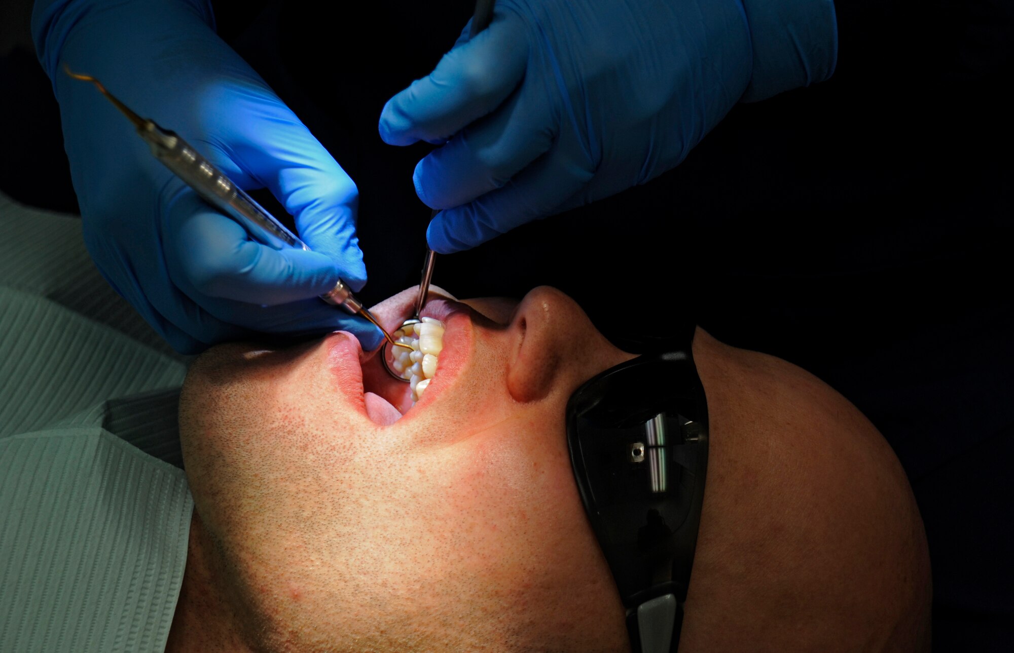 Senior Airman Shane Phipps, 30th Space Wing Public Affairs photojournalist, has his teeth cleaned by Rhodora Pablo, 30th Medical Operations Squadron dental hygienist, Oct. 10, 2014, Vandenberg Air Force Base, Calif. The dental flight, within the 30th Medical Operations Squadron, is currently celebrating October’s National Dental Hygiene month. (U.S. Air Force photo by Airman 1st Class Ian Dudley/Released)