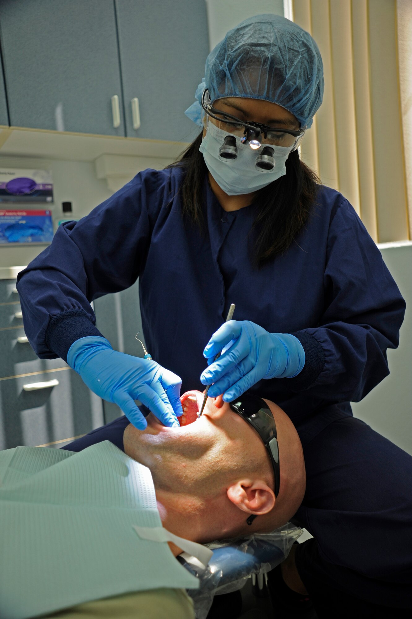 Senior Airman Shane Phipps, 30th Space Wing Public Affairs photojournalist, has his teeth cleaned by Rhodora Pablo, 30th Medical Operations Squadron dental hygienist, Oct. 10, 2014, Vandenberg Air Force Base, Calif. The dental flight, within the 30th Medical Operations Squadron, is currently celebrating October’s National Dental Hygiene month. (U.S. Air Force photo by Airman 1st Class Ian Dudley/Released)