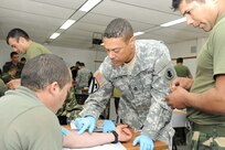 Master Sgt. Dean Dawson (center), a medical operations noncommissioned officer in charge with U.S. Army South’s medical directorate, demonstrates how to administer an IV during a tactical combat lifesaver course subject matter expert exchange Sept. 17 in Toledo, Uruguay. 

Photo by Robert R. Ramon