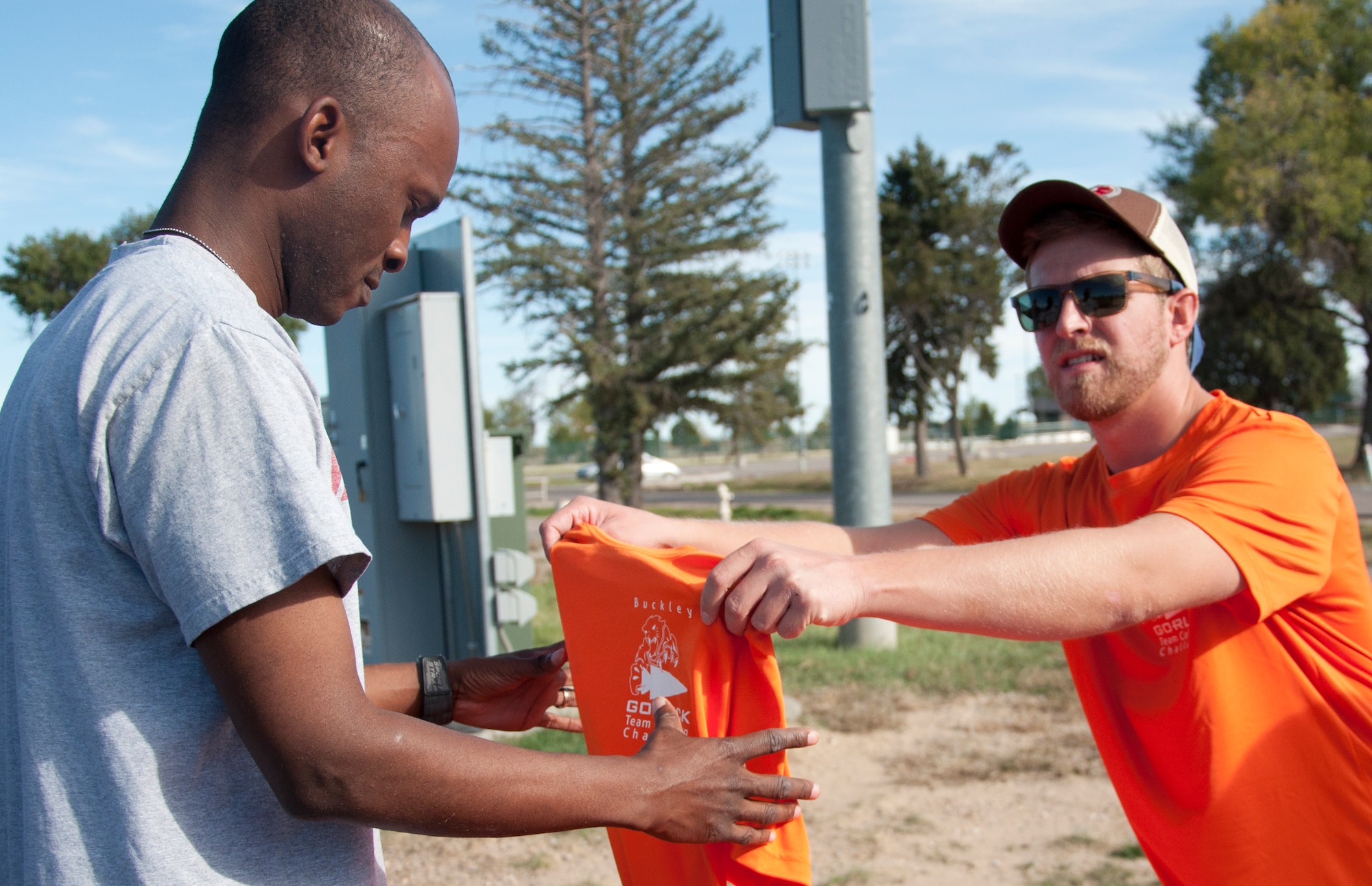 William Link, Buckley Outdoor Recreation Center adventure programmer, hands a T-shirt to Staff Sgt. Phice Richards, Air Reserve Personnel Center, before the beginning of the Team Cohesion Challenge 5K Oct. 7, 2014, at the track on Buckley Air Force Base, Colo. The 5K kicked off the Team Cohesion Challenge, a GORUCK event made available to all Team Buckley members to incorporate the Five C's of Comprehensive Airmen Fitness: Caring, Committing, Connecting, Communicating and Celebrating. (U.S. Air Force photo by Tech. Sgt. Kali L. Gradishar/Released)