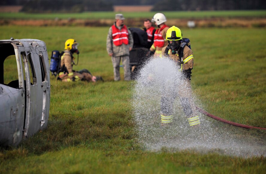 A firefighter from Suffolk Fire and Rescue Service simulates putting out a fire during a Major Accident Response Exercise Oct. 7, 2014, on RAF Honington, England. The MARE tested RAF Mildenhall, RAF Honington and local first responders’ capabilities on what to do after a major aircraft accident. (U.S. Air Force photo/Senior Airman Christine Griffiths/Released)