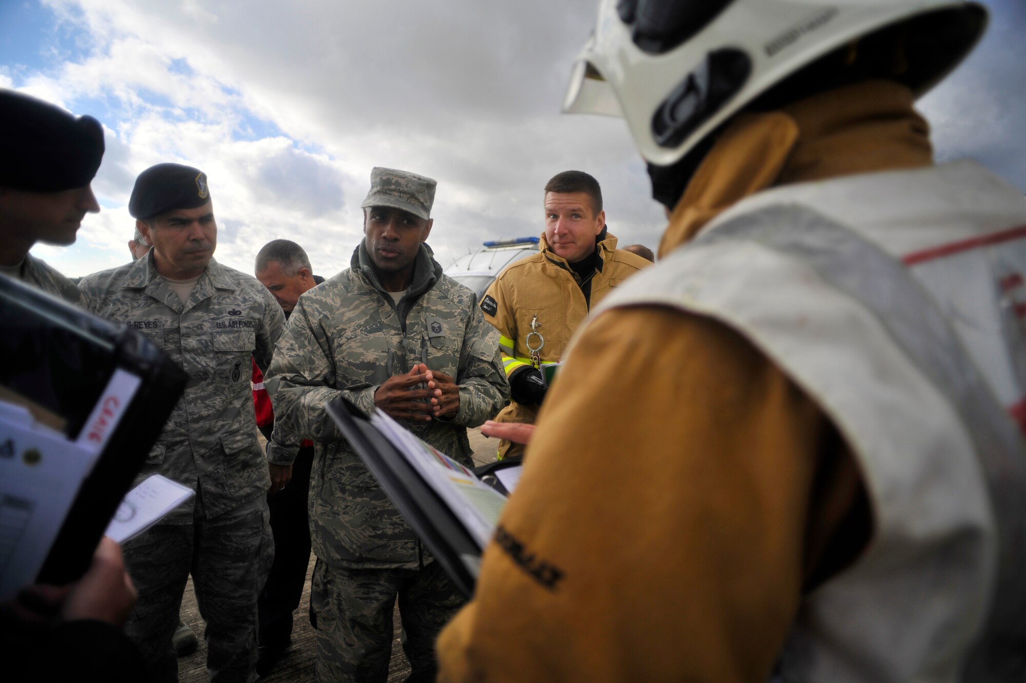 U.S. Air Force Master Sgt. Dion Bullock, third from left,  100th Civil Engineering Squadron Fire Department deputy fire chief from Yuba City, Calif., receives a turnover brief from the initial on scene commander during a Major Accident Response Exercise Oct. 7, 2014, on RAF Honington, England. The MARE tested RAF Mildenhall, RAF Honington and local first responders on what to do after a major aircraft accident. (U.S. Air Force photo/Senior Airman Christine Griffiths/Released)