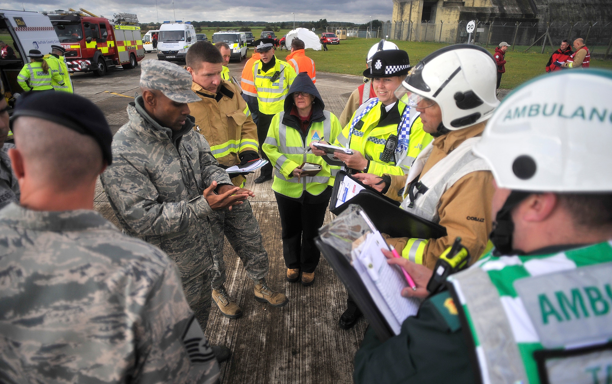 U.S. Air Force Master Sgt. Dion Bullock, second from left, 100th Civil Engineer Squadron Fire Department deputy fire chief, from Yuba City, Calif., receives a turnover brief from the initial on-scene commander, second from right, during a Major Accident Response Exercise Oct. 7, 2014, on RAF Honington, England. The MARE tested RAF Mildenhall, RAF Honington and local first responders on what to do after a major aircraft accident. (U.S. Air Force photo/Senior Airman Christine Griffiths/Released)