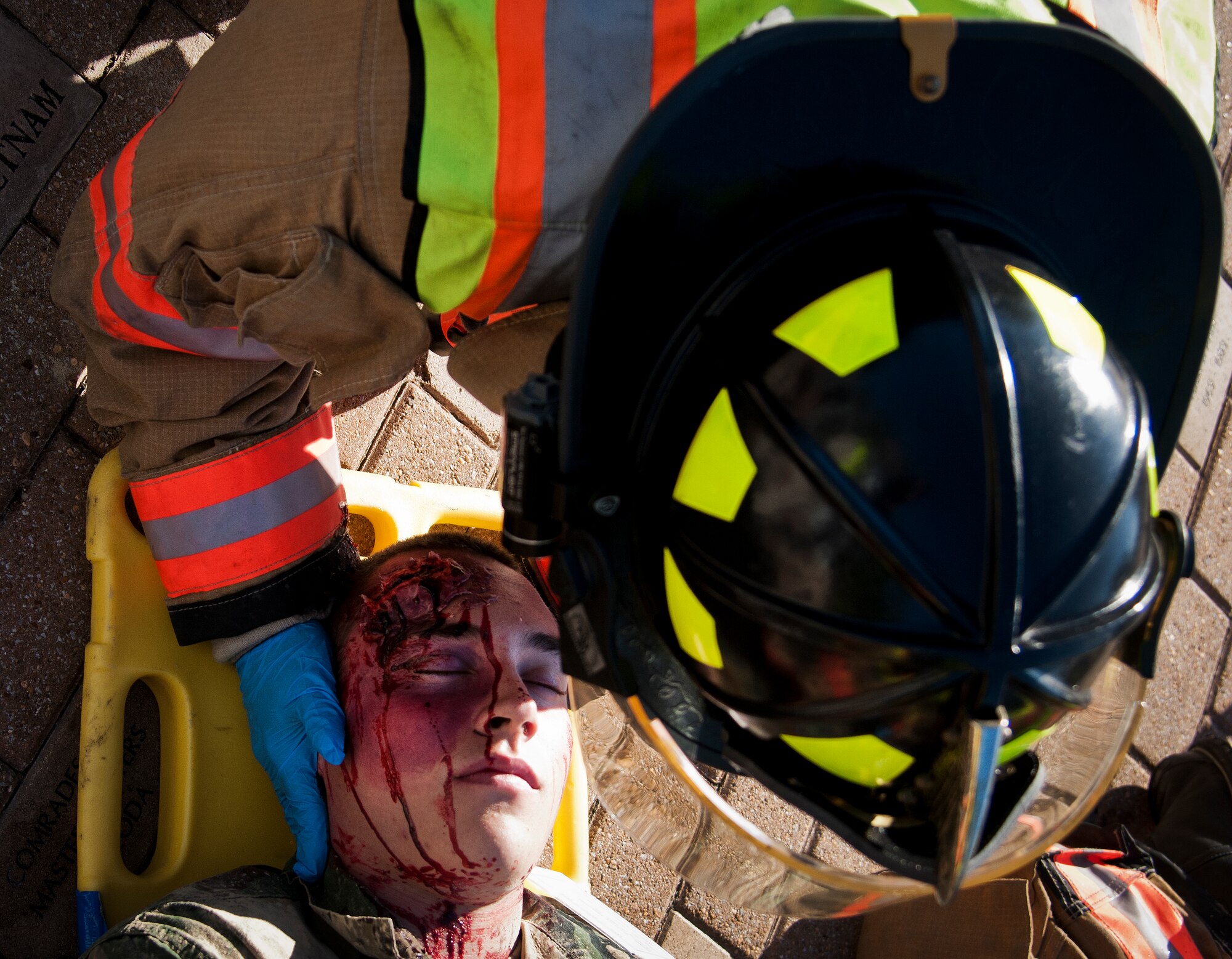 A 96th Test Wing firefighter secures a simulated victim's neck during a major accident response exercise Oct. 7 at Eglin Air Force Base, Fla.  The exercise scenario was a simulated vehicle-borne improvised explosive device was detonated at the explosive ordnance disposal school house killing and injuring students. The exercise helped train Navy EOD School staff, Team Eglin first responders and local emergency crews.  Firefighters and emergency medical technicians responded to the scene to put out the fire and assist the victims.  (U.S. Air Force photo/Samuel King Jr.)