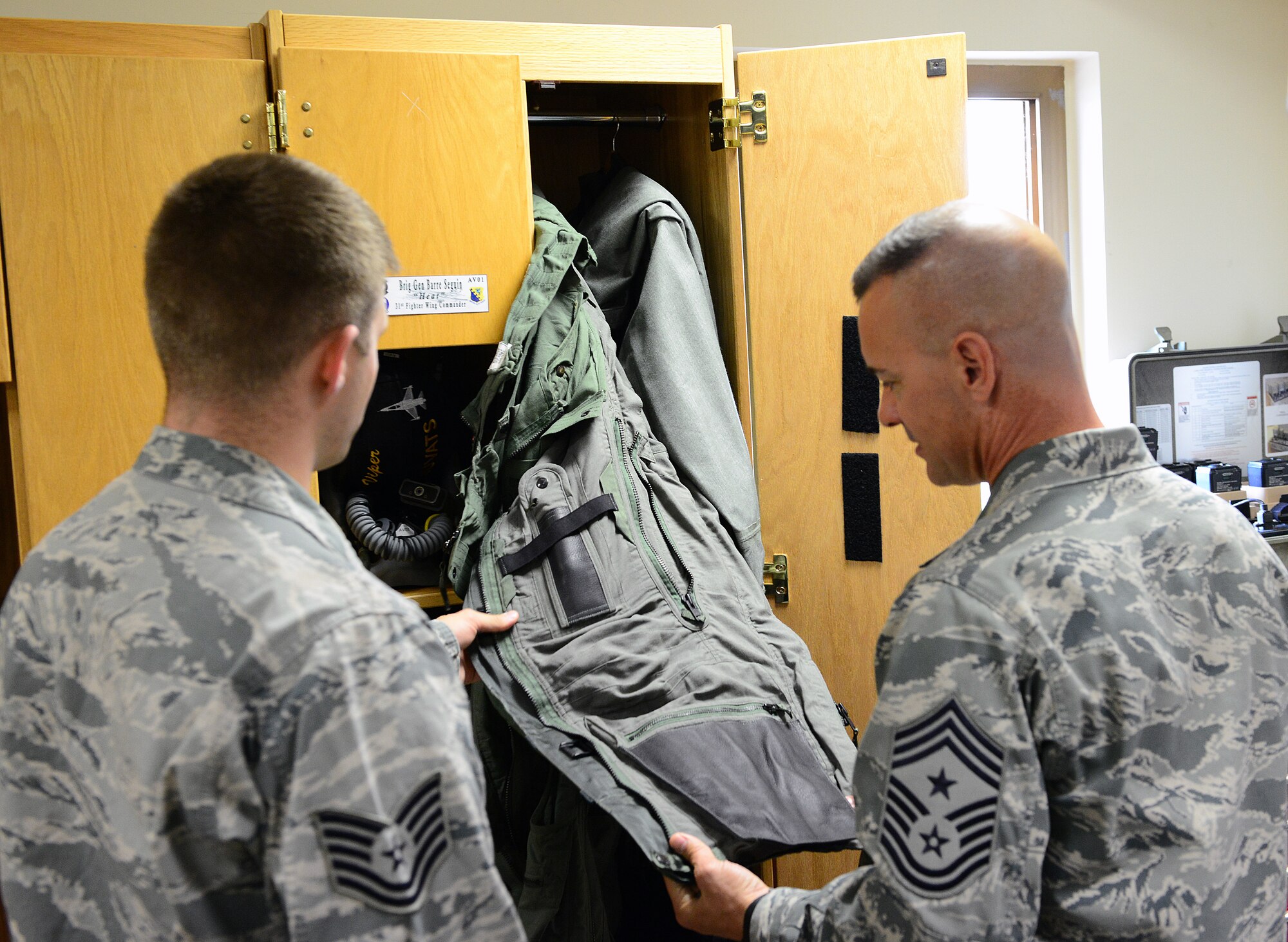 Tech. Sgt. Andrew Nicely, 31st Operations Support Squadron aircrew flight equipment technician, explains the function of a pilot’s G-suit to Chief Master Sgt. Mark Marson, 3rd Air Force command chief, Oct. 8, 2014, at Aviano Air Base, Italy. Marson accompanied Lt. Gen. Darryl Roberson, 3rd Air Force commander, during his first visit here.  (U.S. Air Force photo/Senior Airman Matthew Lotz)