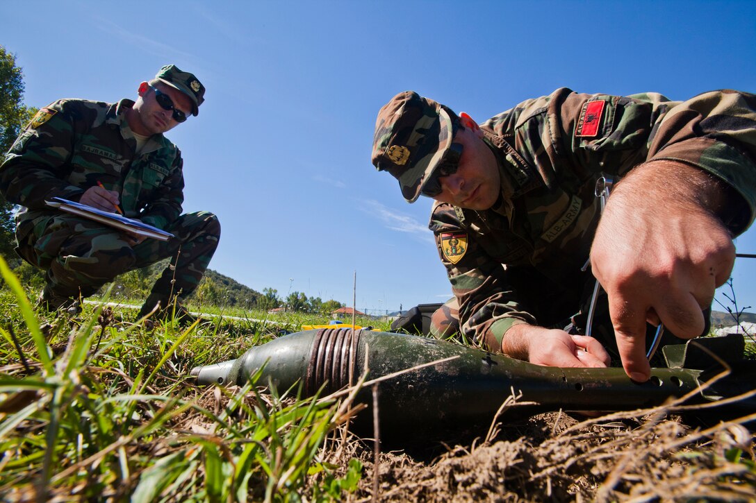 Albanian Army Lance Cpl. Ervin Bajramaj, left, observes 1st Lt. Arlind Nushi’s progress during a practical problem – an EOD process that uses munition replicas to test future EOD technicians at Peze Helmes, Republic of Albania, Sept. 24, 2014. In September 2014, members of the 177th Fighter Wing Explosive Ordnance Disposal team, New Jersey Air National Guard, trained Albanian Army EOD soldiers to become level 1 EOD trainers. New Jersey National Guard Airmen and Soldiers have been training their Albanian counterparts for more than 20 years as part of the State Partnership Program between the state of New Jersey and the Republic of Albania. (U.S. Air National Guard photo by Master Sgt. Mark C. Olsen /Released)