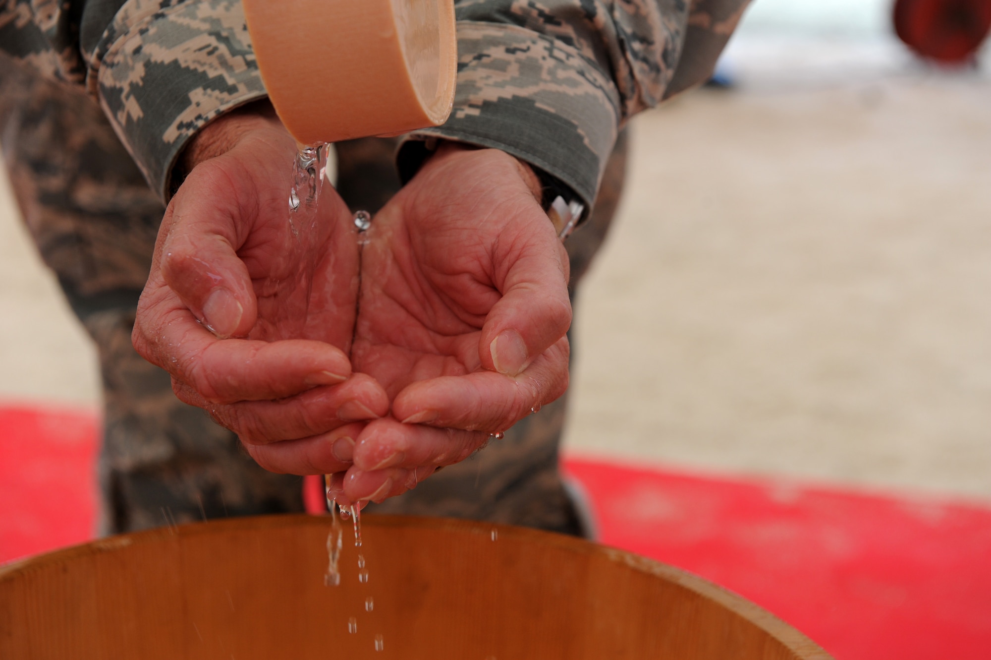 All attendees of the ground breaking ceremony purified their hands so the grounds could be blessed properly before entering the event on Kadena Air Base, Japan, Oct. 2, 2014. After the ceremony, attendees met back together at the Kadena Officers' Club for lunch where Sarabjit Singh Narula, Gilbane Federal president, spoke about the new project. (U.S. Air Force photo by Airman 1st Class Stephen G. Eigel)