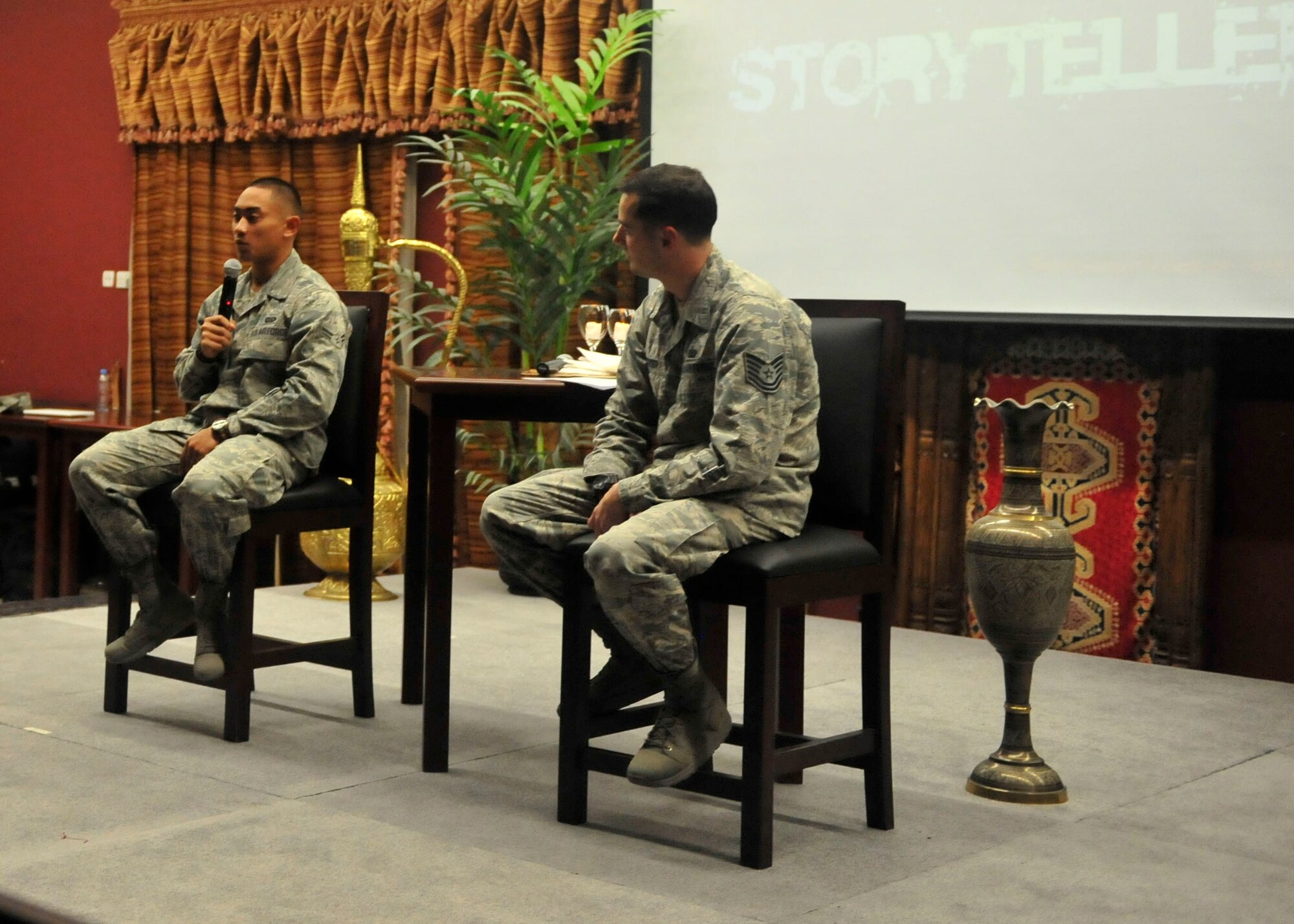 U.S. Air Force Tech. Sgt. James Sanders, 609th Combined Air Operations Center noncommissioned officer in-charge of day shift targets and Airman 1st Class Zachary, 340th Expeditionary Air Refueling Squadron intelligence journeyman, speak during a Storytellers event at Al Udeid Air Base, Qatar, Oct. 4, 2014. Zachary was one of four participants in Storytellers, an event created to provide a forum where Airmen can share experiences and learn about one another, promoting understanding throughout the Air Force. (U.S. Air Force photo by Senior Airman Colin Cates)