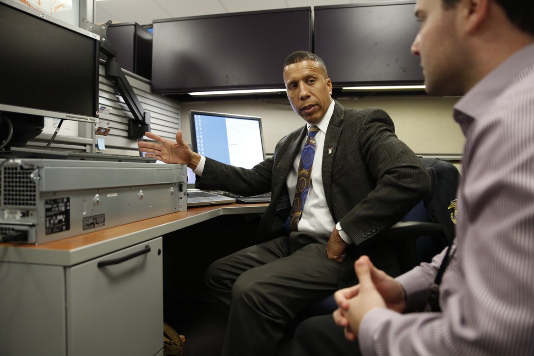 Luis Velazquez reviews modeling and simulation principles with recent college graduate Alex Solomon at Marine Corps Systems Command on Marine Corps Base Quantico, Virginia. Velazquez' father laid the foundation for his son's future success in Humacao, Puerto Rico. Today, Luis is the deputy modeling and simulations lead at MCSC. 