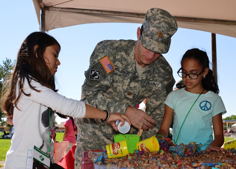 BERNALILLO, N.M., -- District Deputy Commander Maj. Jason Melchior works with two Girl Scouts as they build a dam at the District’s Camporee booth.  