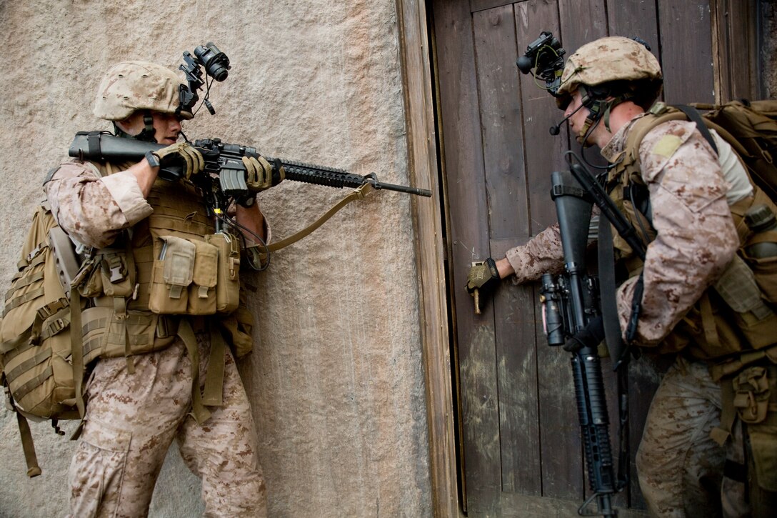 MARINE CORPS TRAINING AREA BELLOWS, Hawaii — Lance Cpl. Matthew Newland and Cpl. Jeremy Atkins, members of a radio reconnaissance team for Bravo Company, 3rd Radio Battalion, communicate through hand and arm signals before entering a room in a simulated mission abroad Marine Corps Training Area Bellows, Oct. 7, 2014. Eight Marines from Bravo Company are currently participating in a Radio Reconnaissance Operations Course. Six of the Marines will continue on to support the 31st Marine Expeditionary Unit. (U.S. Marine Corps photo by Lance Cpl. Brittney Vella)