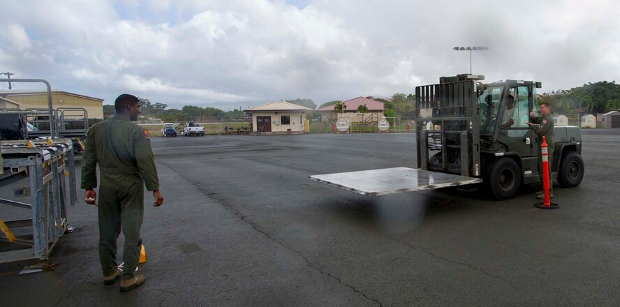 Airman 1st Class Cody Bishop, 535th Airlift Squadron loadmaster, battles the rain to assist a 10K driver with correctly placing an empty palette as part of a friendly competition during Operation Aircrew Orientation at Joint Base Pearl Harbor-Hickam, Hawaii, Oct. 9, 2014. Operation Aircrew offered members of the 535th Airlift Squadron a behind-the-scenes look at 735th Air Mobility Squadron operations. During the tour, aircrew members were educated on the inner workings of an air mobility squadron including passenger services, air freight, Air Terminal Operations Center and Air Mobility Command Control Center. (U.S. Air Force photo by Tech. Sgt. Terri Paden)