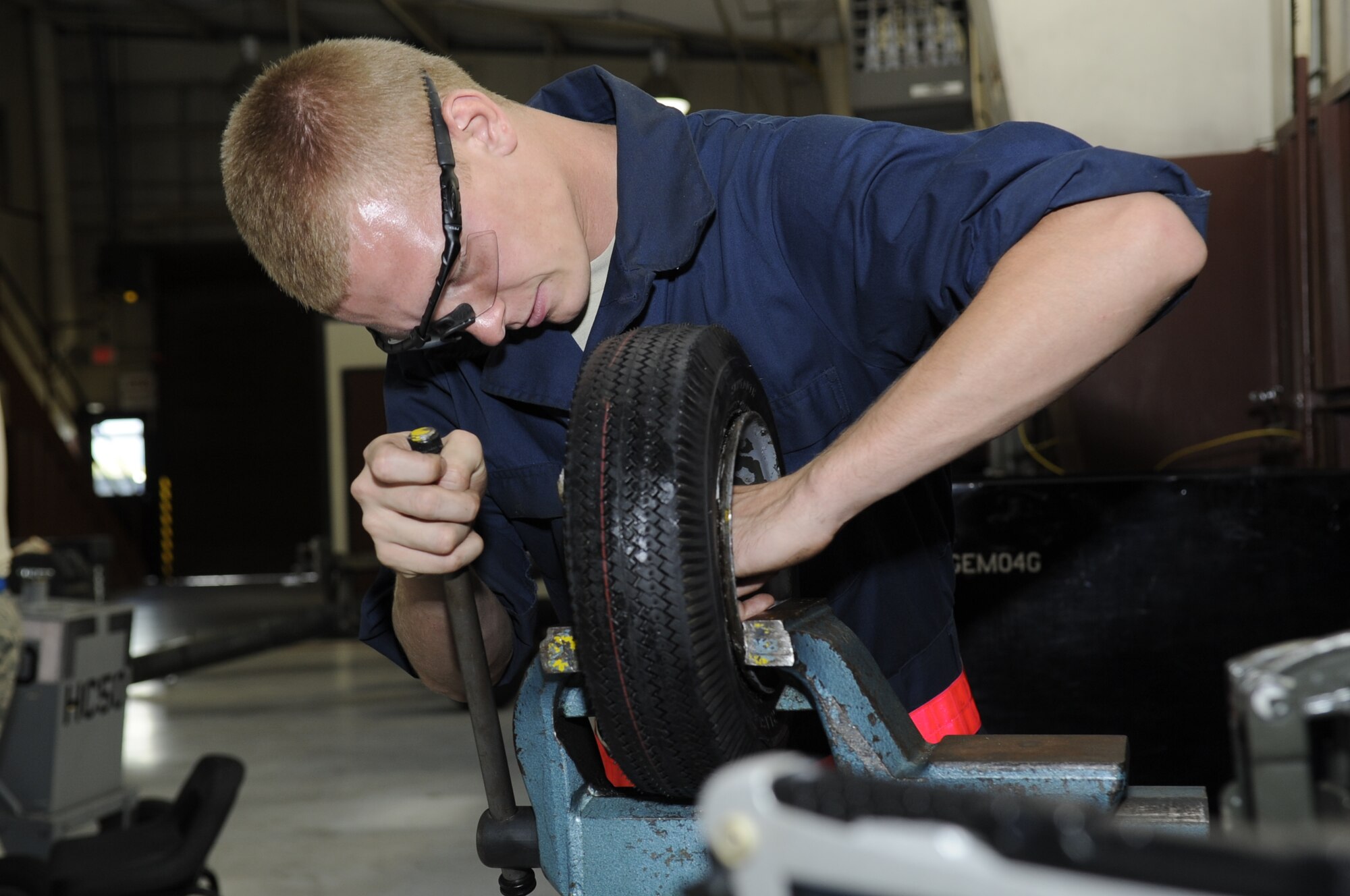 U.S. Air Force Airman 1st Class Jonathan Baker, 355th Equipment Maintenance Squadron aerospace ground equipment journeyman, uses a bench vise to lock a wheel in place in order to replace its inner tube at Davis-Monthan Air Force Base, Ariz., Oct. 9, 2014. Replacing the tube can be difficult because if it is not installed correctly, it can get pinched in between the steel rim and the tire, causing the tube to explode when inflated. (U.S. Air Force photo by Airman 1st Class Betty R. Chevalier/Released)