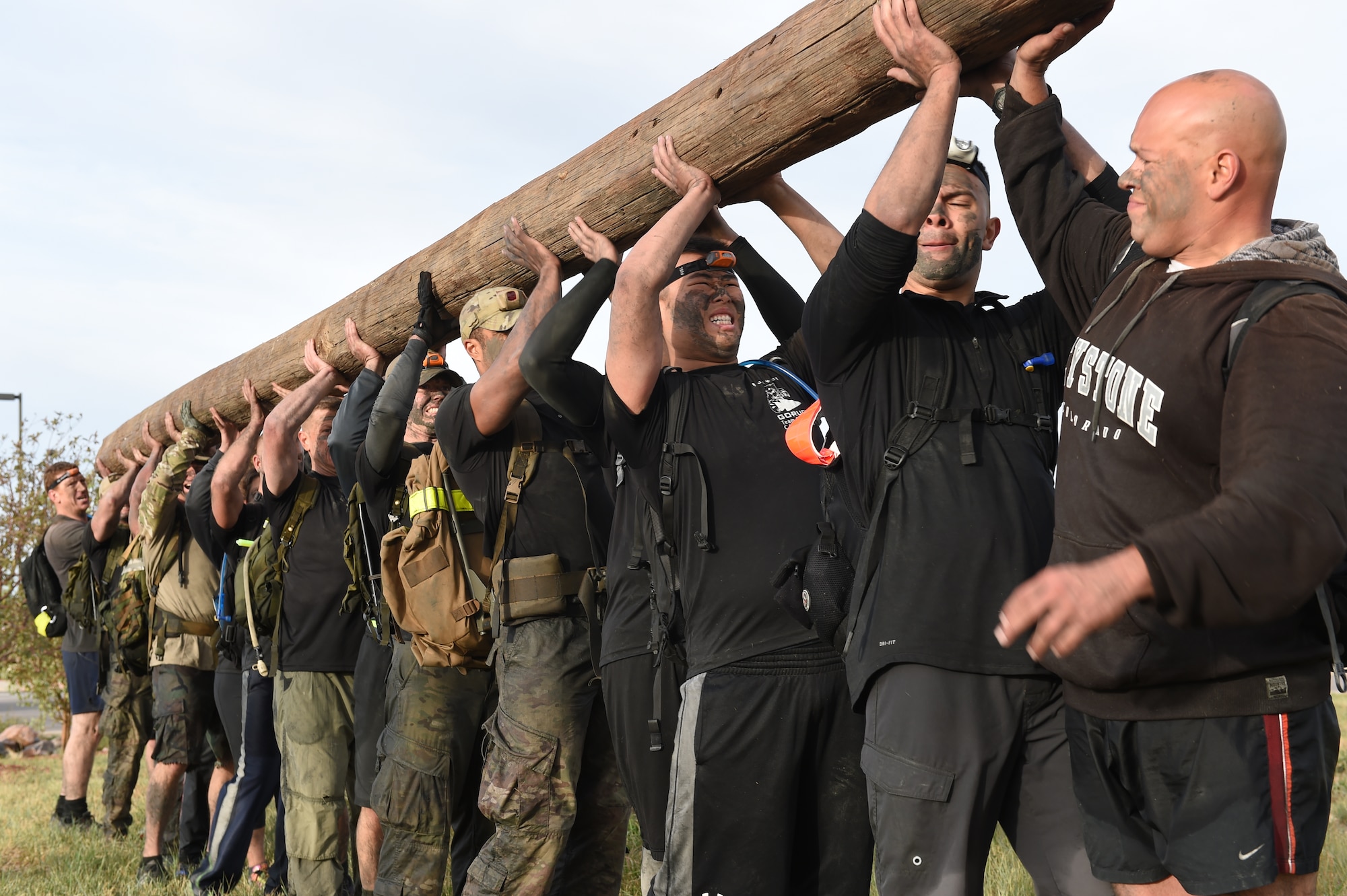 Buckley’s Team Cohesion Challenge team lifts a wooden telephone pole above their heads Oct. 8, 2014, during the Team Cohesion Challenge on Buckley Air Force Base, Colo. The five-hour long challenge, hosted by GORUCK, began long before sunrise and consisted of crawling through water drains and swimming through Lake Williams with 25-pound rucksacks on their backs. (U.S. Air Force photo by Airman 1st Class Samantha Saulsbury/Released)