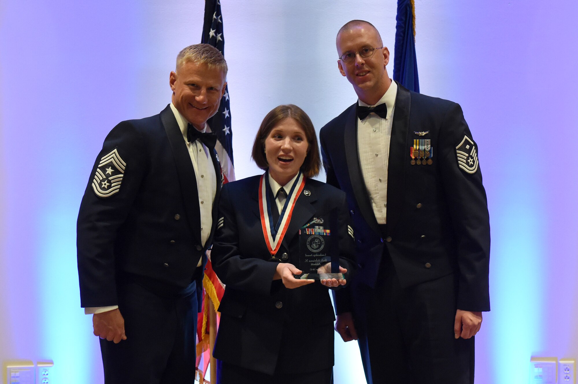 Senior Airman Adriana Abbott, Aerospace Data Facility-Colorado, center, receives the Leadership Award during the Buckley Airman Leadership School Class 14-G graduation Oct. 9, 2014, at the Leadership Development Center on Buckley Air Force Base, Colo. This award is presented to the graduate who displays the best overall characteristics of an effective leader. (U.S. Air Force photo by Airman Emily E. Amyotte/Released)