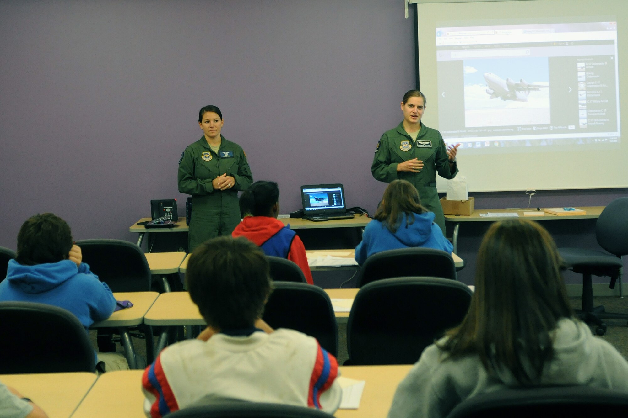 Capt. Kayla Hill (left), 7th Airlift Squadron pilot and Capt. Morgan Talley, 8th AS pilot, brief 8th-grade students on the capabilities of the C-17 Globemaster III Oct. 9, 2014, during the Clover Park Technical College Math Conference in Lakewood, Wash. Pilots and loadmasters from the 62nd Airlift Wing’s flying squadrons taught more than 100 8th-grade students how math is used in aviation. (U.S. Air Force photo/Airman 1st Class Jacob Jimenez)