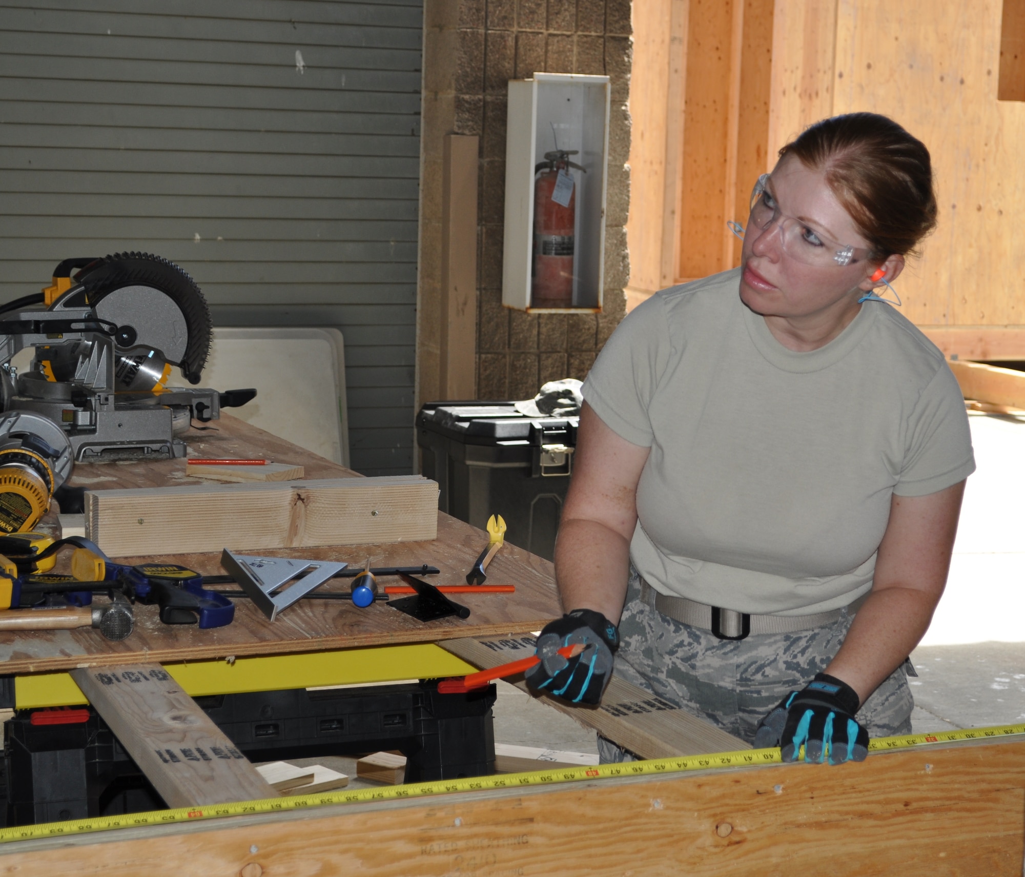 Senior Airman Adriana Pop, 349th Civil Engineer Squadron structural specialist, marks boards for cutting during recent construction of the "Build it, Burn it, Blow it Up" shed. (U.S. Air Force photo by Ellen Hatfield)