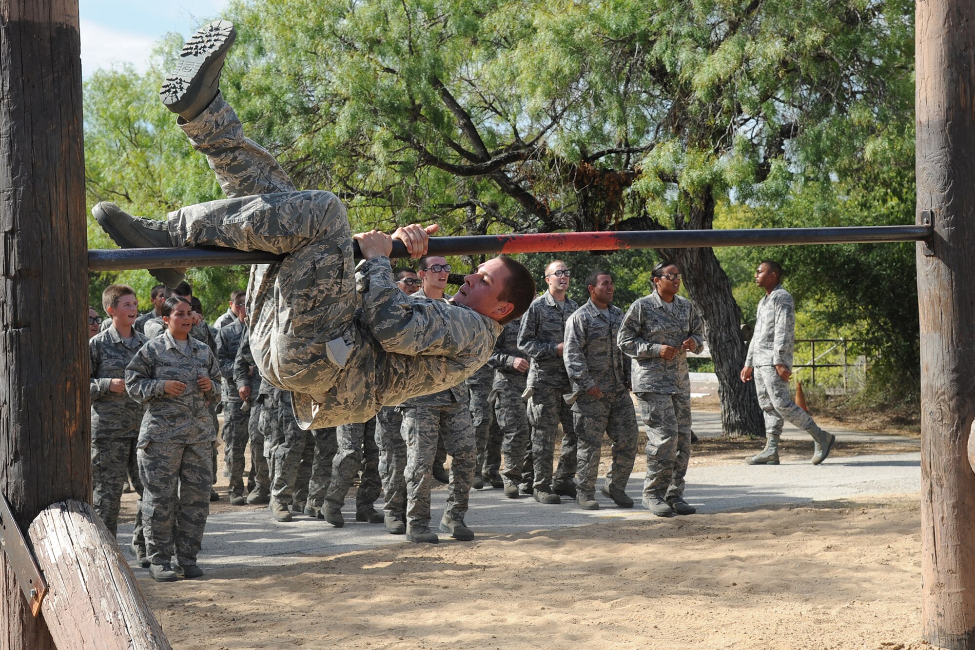 Basic military trainees swing around a bar as part of the basic military training obstacle course at Sept. 24, 2014 Joint Base San Antonio-Lackland. The obstacle course was about a mile to a mile and a half long depending on what 14 obstacles were open. The two water obstacles were closed seasonally. The course was permanently closed the same day and new one was integrated into the Creating Leaders, Airmen, and Warriors – or CLAW – mission and became fully operational Sept. 29. (U.S. Air Force photo by Senior Airman Krystal Jeffers/Released)