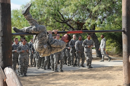 Basic military trainees swing around a bar as part of the basic military training obstacle course at Sept. 24, 2014 Joint Base San Antonio-Lackland. The obstacle course was about a mile to a mile and a half long depending on what 14 obstacles were open. The two water obstacles were closed seasonally. The course was permanently closed the same day and new one was integrated into the Creating Leaders, Airmen, and Warriors – or CLAW – mission and became fully operational Sept. 29. (U.S. Air Force photo by Senior Airman Krystal Jeffers/Released)