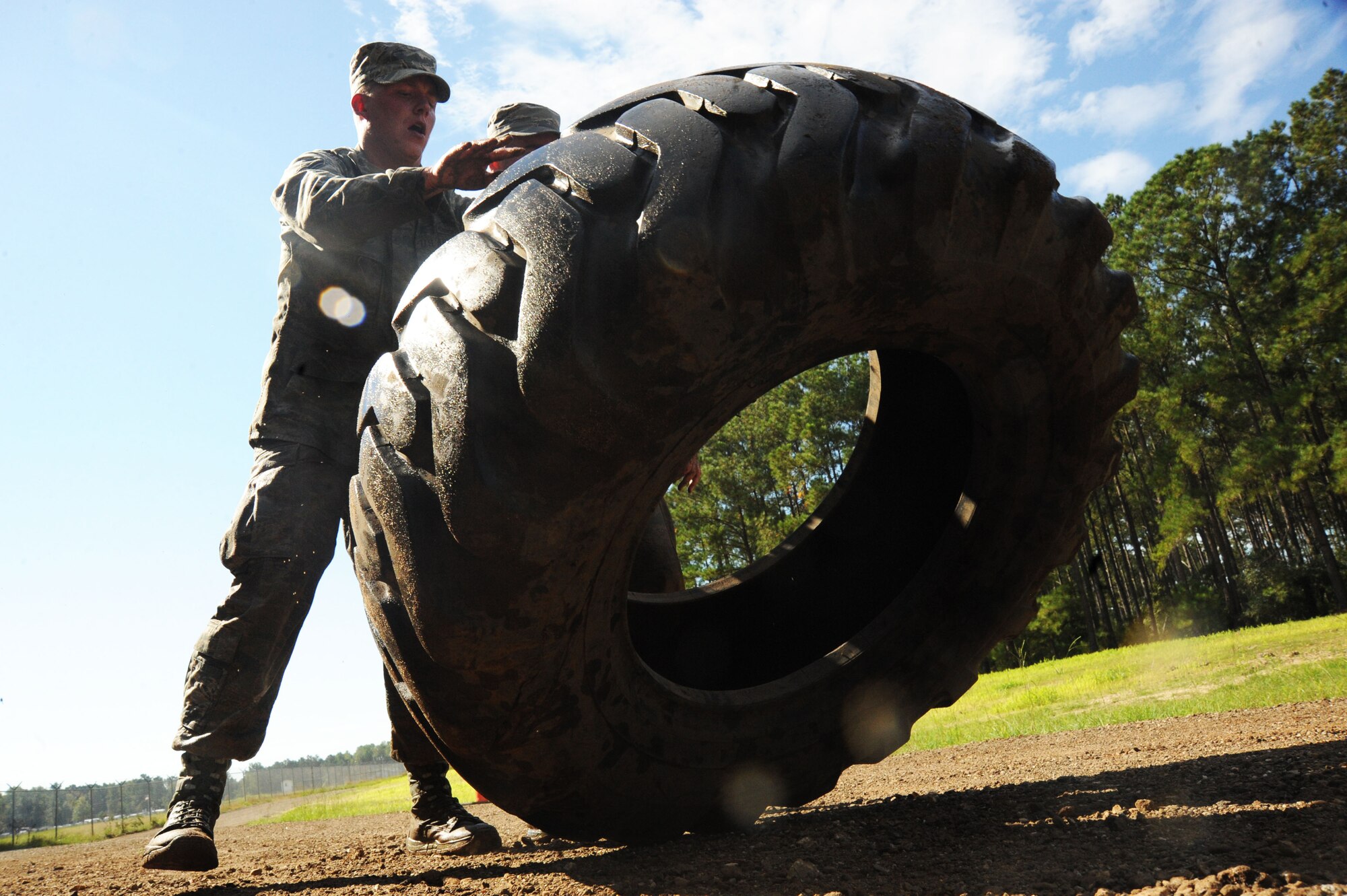 U.S. Air Force Airman 1st Class Robert Rosensteel and Senior Airman Patrick Lehane, 20th Security Forces Squadron entry controllers, push a tire during a Defenders Edge Challenge at Shaw Air Force Base, S.C., Oct. 8, 2014. During the challenge, Airmen faced obsticales which tested their physical fitness, mental, and shooting abilities. (U.S. Air Force photo by Airman 1st Class Michael Cossaboom/Released)