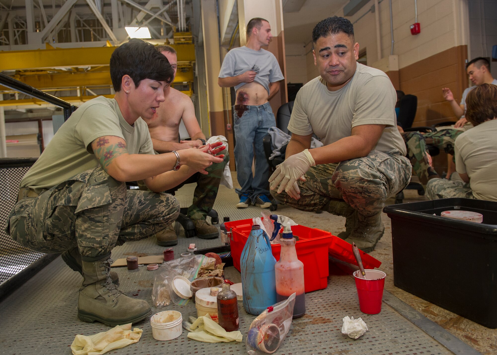 Members of the 49th Medical Group discuss the application process of a simulated bullet wound on a victim participant during an active shooter exercise at Holloman Air Force Base, N.M., Oct. 9. Holloman exercises to maintain readiness in order to respond to emergencies such as active shooters. Members from the 49th Security Forces Squadron, 49th Civil Engineer Squadron and the 49th Medical Group were able to quickly respond to the exercise scenario, neutralize the threats and evacuate the victims. (U.S. Air Force photo by Airman 1st Class Aaron Montoya / Released) 