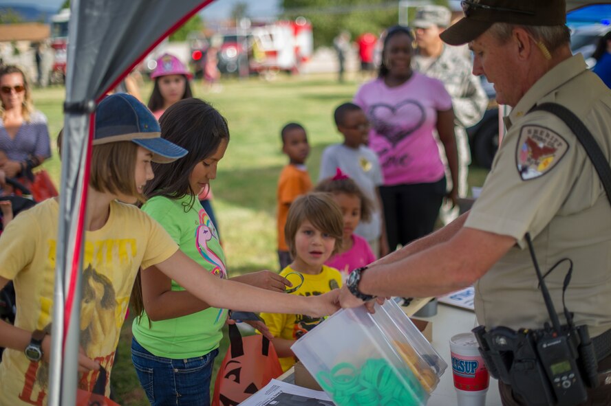 The Otero County Sheriff’s Department passes out informational flyers and free gifts to Team Holloman members during the National Night Out event hosted by the Soaring Heights community office at Holloman Air Force Base, N.M., Oct. 7. The night out event is a community-based event that increases awareness about safety programs in local communities, such as drug prevention, neighborhood watch and other anti-crime efforts. This is the seventh year Soaring Heights has hosted the event and brought together 11 law enforcement, fire protection and community support agencies to provide Holloman residents information and child safety material. The National Night Out is also an opportunity for the 49th Security Forces Squadron to demonstrate how they keep the base safe through defensive tactics and military working dog demonstrations. (U.S. Air Force photo by Airman 1st Class Aaron Montoya / Released)