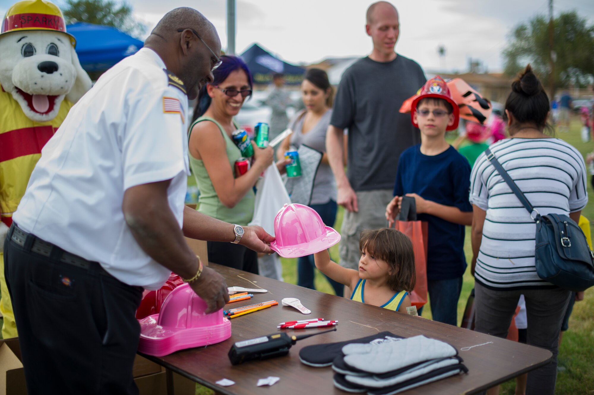 Harvey Stevens, 49th Civil Engineer Squadron Fire Protection Flight assistant chief of fire protection, provides information to parents and gifts to children during the National Night Out event hosted by the Soaring Heights community office at Holloman Air Force Base, N.M., Oct. 7. The night out event is a community-based event that increases awareness about safety programs in local communities, such as drug prevention, neighborhood watch and other anti-crime efforts. This is the seventh year Soaring Heights has hosted the event and brought together 11 law enforcement, fire protection and community support agencies to provide Holloman residents information and child safety material. The National Night Out is also an opportunity for the 49th Security Forces Squadron to demonstrate how they keep the base safe through defensive tactics and military working dog demonstrations. (U.S. Air Force photo by Airman 1st Class Aaron Montoya / Released)
