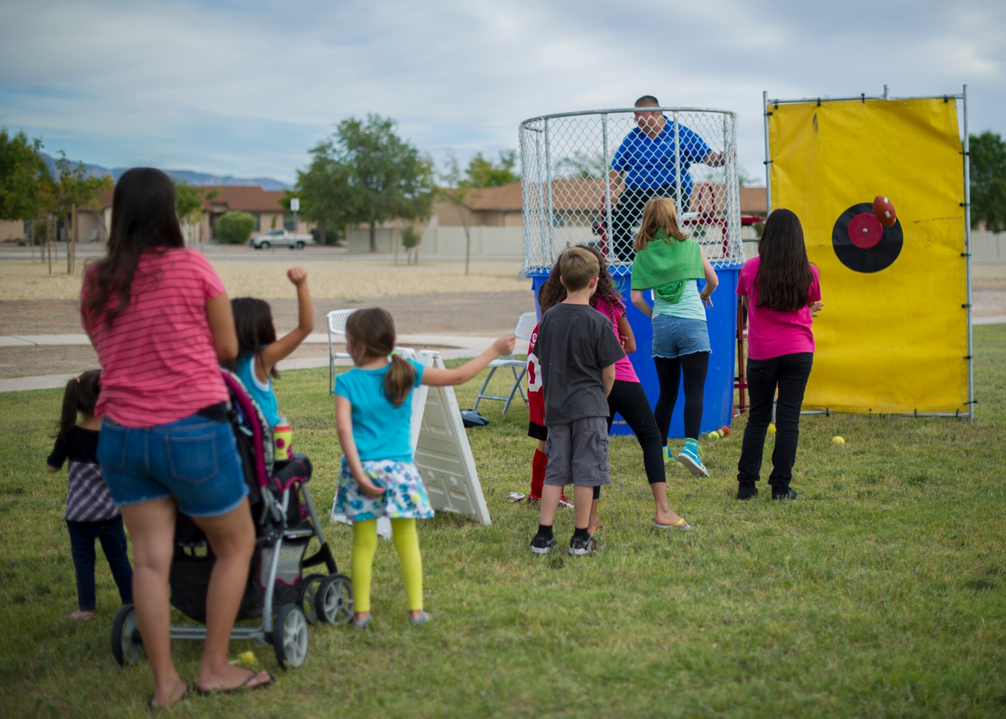 Holloman Airmen and their families participate in a dunk tank challenge during the National Night Out event hosted by the Soaring Heights community office at Holloman Air Force Base, N.M., Oct. 7. The night out event is a community-based event that increases awareness about safety programs in local communities, such as drug prevention, neighborhood watch and other anti-crime efforts. This is the seventh year Soaring Heights has hosted the event and brought together 11 law enforcement, fire protection and community support agencies to provide Holloman residents information and child safety material. The National Night Out is also an opportunity for the 49th Security Forces Squadron to demonstrate how they keep the base safe through defensive tactics and military working dog demonstrations. (U.S. Air Force photo by Airman 1st Class Aaron Montoya / Released)