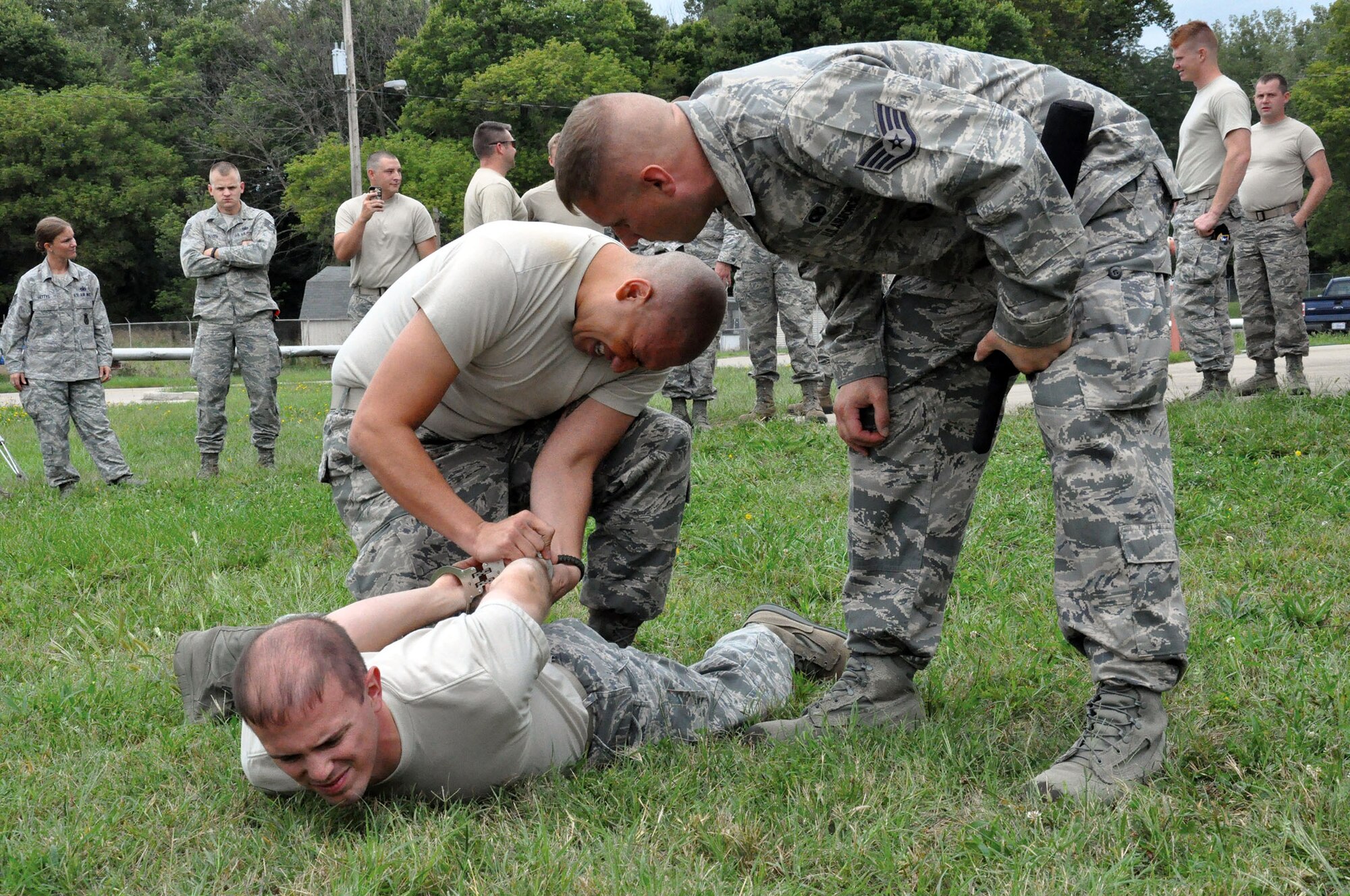 WRIGHT-PATTERSON AIR FORCE BASE, Ohio - Staff Sgt. Julio Medina, 445th Security Forces fire team member, handcuffs Tech. Sgt. Ryan LaMarr after Medina was sprayed in the face with Oleoresin Capsicum (OC) pepper spray here Sept. 6, 2014. Staff Sgt. Ryan Steele (right) observes and instructs. All members of the 445 SFS must experience the OC pepper spray once as part of annual less-than-lethal force training. (U.S. Air Force photo/Capt. Elizabeth Caraway)