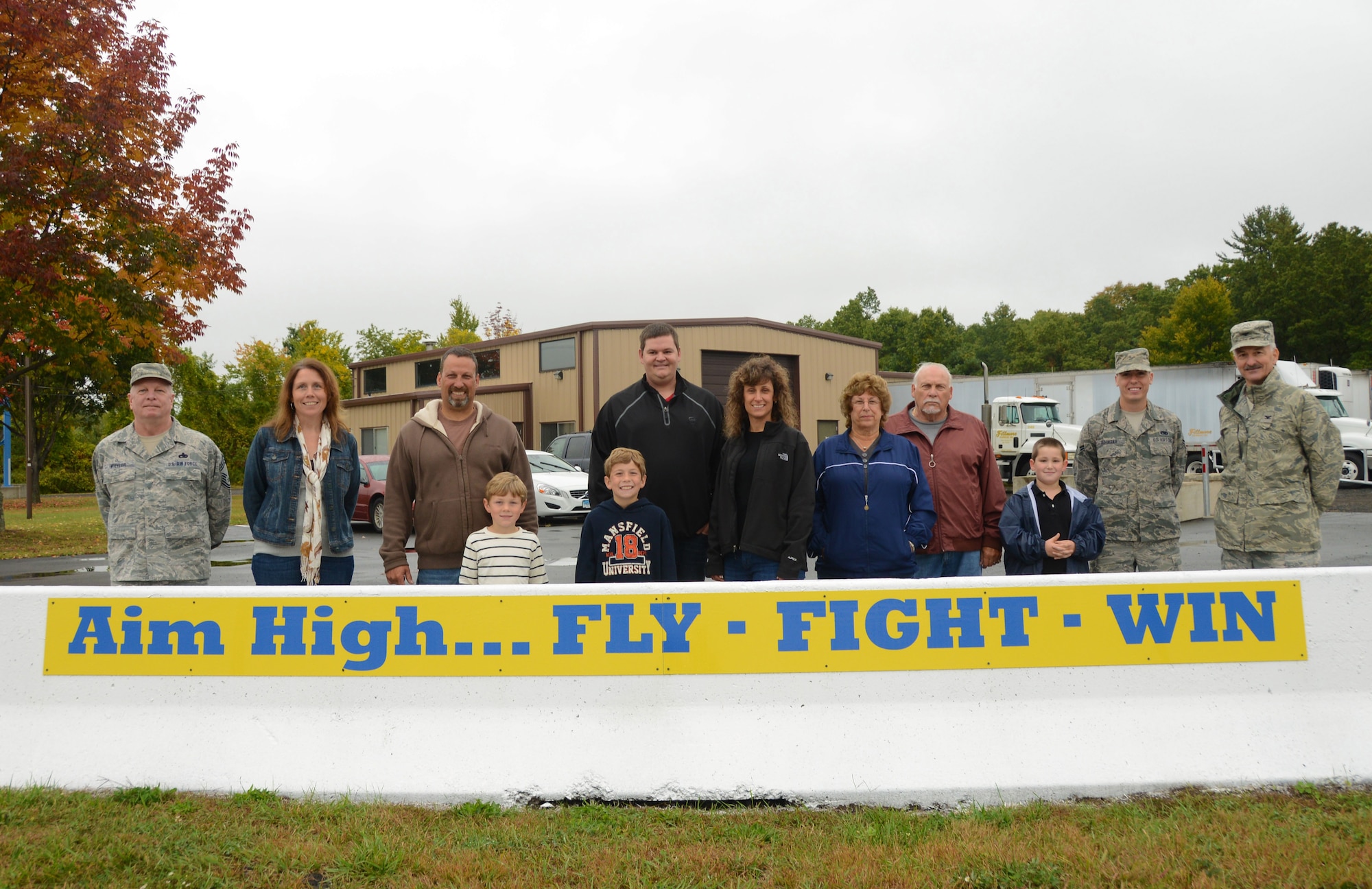 (Uniformed Airmen from left to right) Chief Master Sgt. Patrick Wheeler and Airman 1st Class Eric Buhagiar, both of the 103rd Maintenance Squadron, along with Col. Frederick Miclon, 103rd Airlift Wing vice commander, pose with Fillmore Express Inc. employees and their families behind one of the signs company employees posted outside of their work place in support of the Airmen assigned to the Bradley Air National Guard Base, East Granby, Conn., Oct. 4, 2014. (Air National Guard photo by Senior Airman Jennifer Pierce)